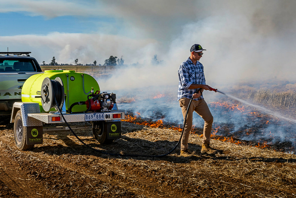 A man is using a fire patrol trailer to extinguish a fire in the rice field.