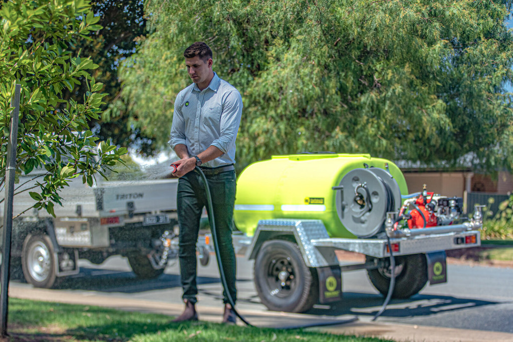Man is using a Water cart trailer to water plants